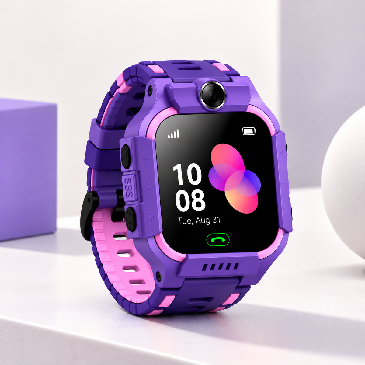 A purple and pink rugged kids' smartwatch with a black display screen, shown on a clean white surface with a purple box and white sphere in the background.