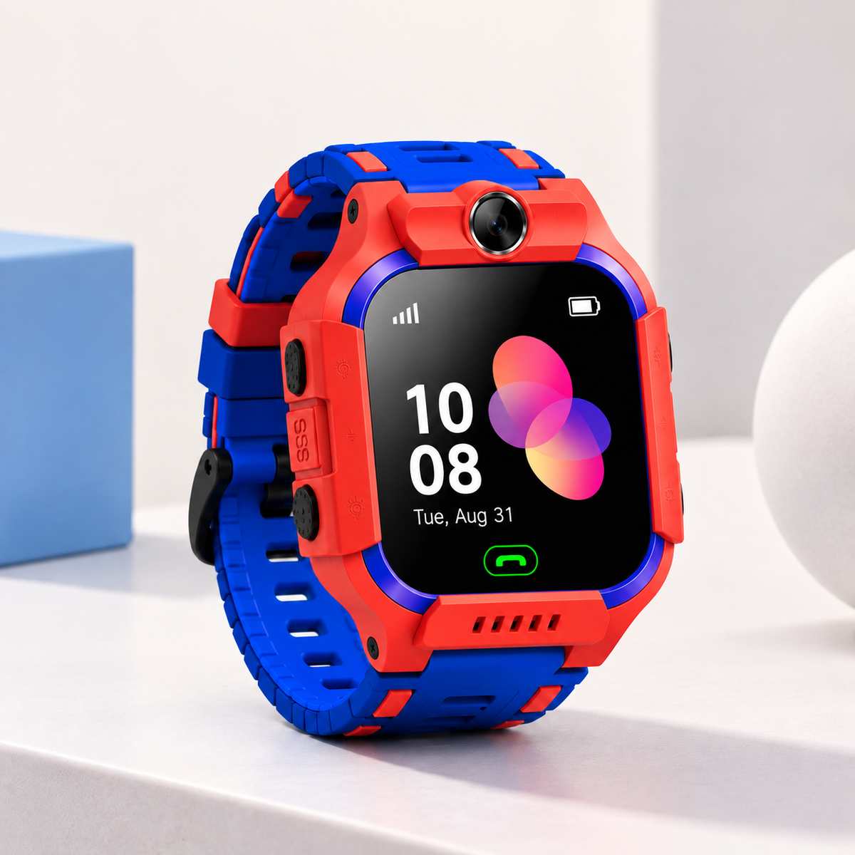 A kids' smartwatch with a bright red and blue protective case and matching strap, shown on a clean white surface with a light blue box in the background.