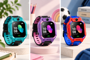 Three kids' smartwatches with colorful protective casings are displayed side by side on pedestals. The watches have black screens and straps, with turquoise, purple, and red-orange colorways.